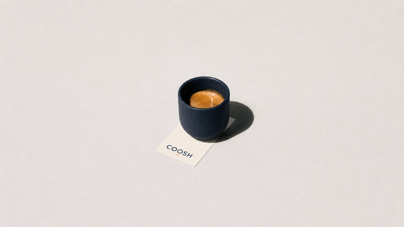 فنجان Espresso كحلي مع بطاقة COOSH على سطح فاتح