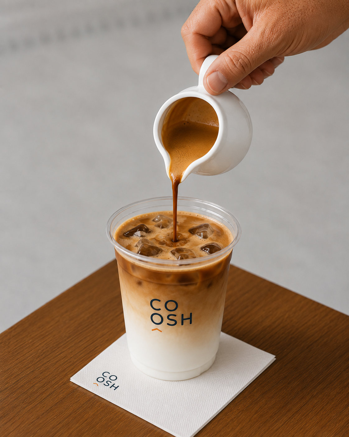 Iced Latte في كوب COOSH الشفاف فوق قاعدة بالشعار