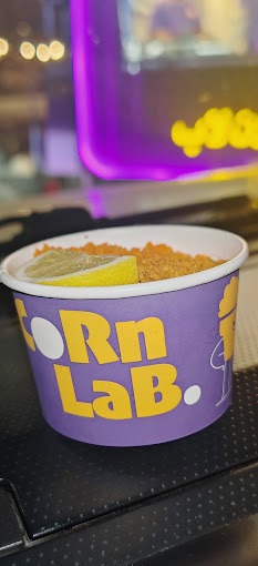كوب CornLab البنفسجي بالشعار الأصفر، مليء بالذرة