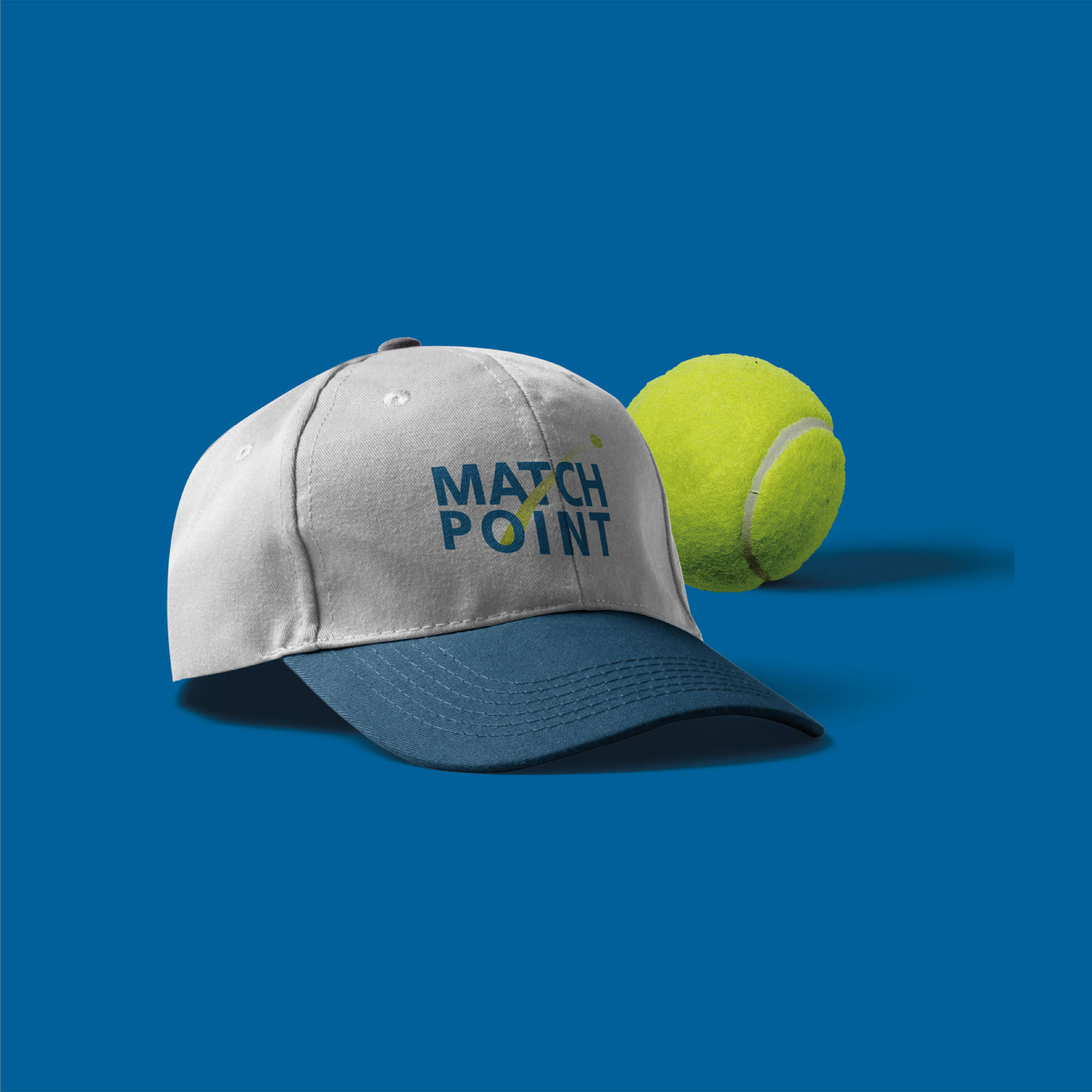 قبعة رمادية بشعار Match Point بجانب كرة تنس على الأزرق